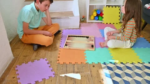 Kids playing backgammon on colorful floor mats at home Stock Footage 290052392