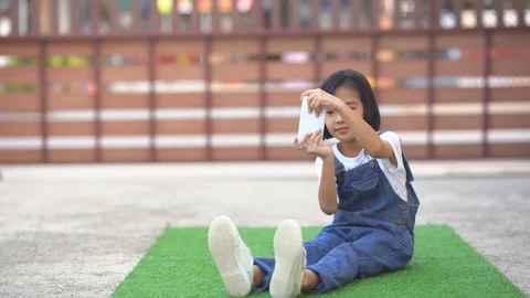 Kids playing smartphone on artificial grass on ground area of home  Vídeos de archivo 129581383