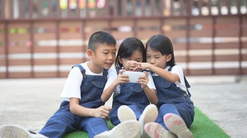 Kids playing smartphone on artificial grass on ground area of home  Stock-Footage 129581403