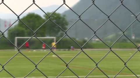 Kids playing soccer looking through fence 스톡 동영상 13370229
