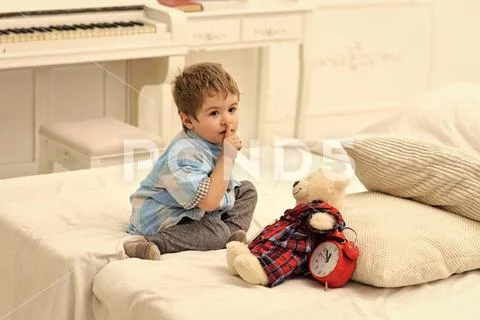 Kids playing with toys. Child in bedroom with silence gesture. Kid put plush Stock Photos
