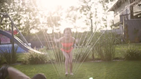 Kids playing with water sprinkler in garden Stock Footage