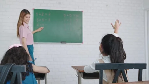 Kids raising hands teacher explaining lesson functioning in classroom at school. Video stock 248546704