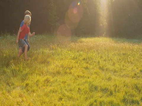 Kids running over a field while sun goes down Stock Footage 82917137