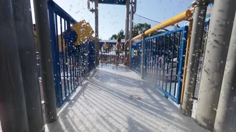 Kids running through a splash zone at a water park on a sunny day. Water Stock Footage 316405118