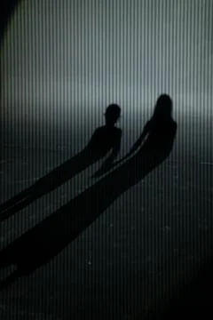 Kid's shadows on wall. shadow of two children, boy and girl on striped gray b Stock Photos