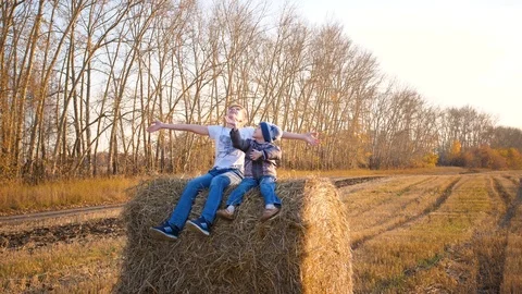 The kids sit on the haystack. They play and laugh.Countryside. Sunset Vidéo 118295347