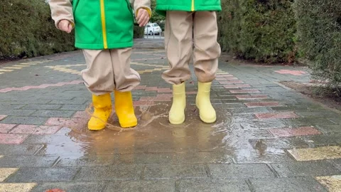 Kids standing in puddle after rain, puddle surface ripples, puddle reflections Stock Footage 328352113