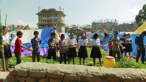 Kids standing in a row and passing bricks at earthquake refugee camp Stock Footage 77451632