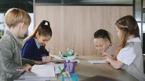 Kids study and work on homework at a table during late afternoon in a modern Stock Footage 331305450