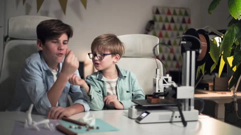 Kids at a table discuss and examine parts printed on a 3D printer Stock Footage 335374943