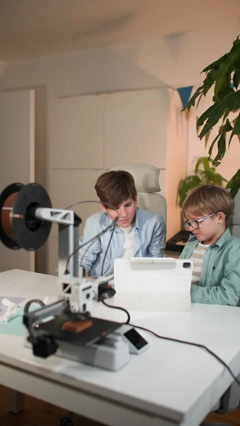 The kids at a table with a work 3D printer, examine already printed parts Stock Footage 335393283