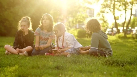 Kids throw grass. Back to school. Four pupils during the school break, sitting Stock Footage 111713823