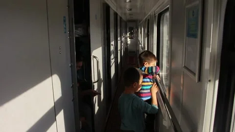 Kids on train corridor looking out of window holding handrail sleeper car Stock-Footage 145729678