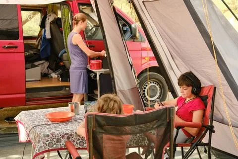 Kids using gadgets while mother cooking in campsite Stock Photos