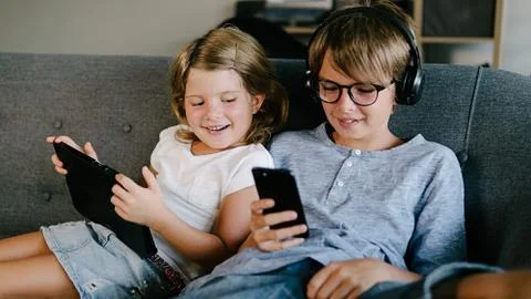 Kids Using Phone in Sofa Stock Photos