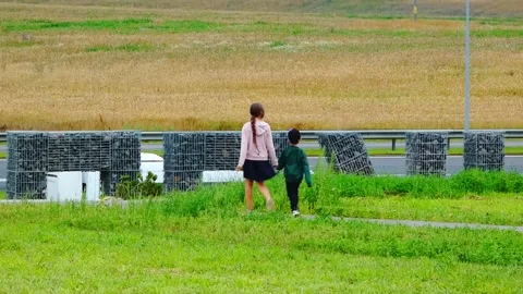 Kids walking on a path in a field holding hands during a sunny day in the countr Stock Footage 337451751