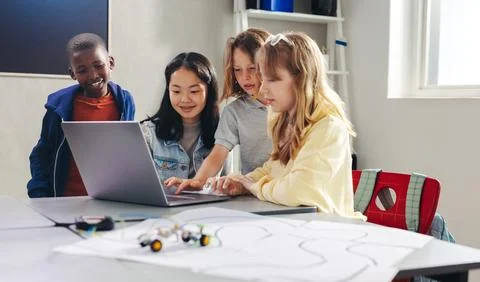 Kids working together to program a robot car with a laptop in a computer sc.. Stock Photos