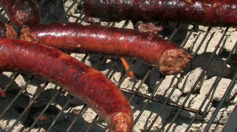 Kielbasa sausage simmering on a flaming grill Stock Footage