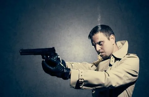 Killer standing on dark background aiming before shooting Stock Photos