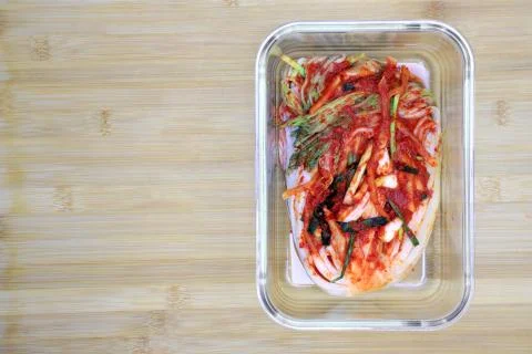 Kimchi cabbage in a glass rectangular bowl on wooden background, top view, Ko Stock Photos