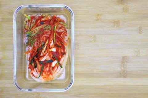 Kimchi cabbage in a glass rectangular bowl on wooden background, top view, Ko Stock Photos