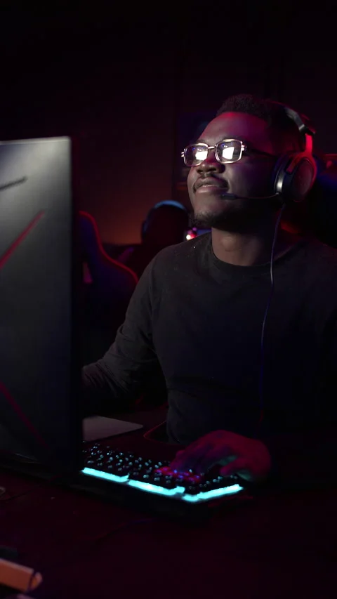 A kind dark-skinned guy plays a video game on the computer, he talks to his Stock Footage 151497363