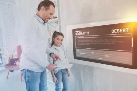 Kind father smiling while showing a tablet to his daughter Stock Photos