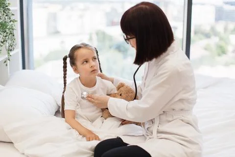 Kind nurse using stethoscope to check up preschool girl Stock Photos