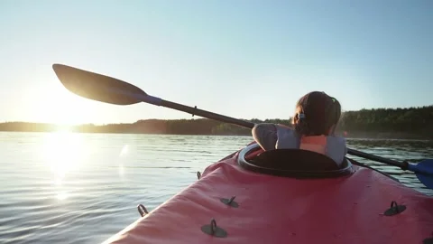 Kindergartener child learning to sail small red kayak along large tranquil lake Stock Footage 153289488