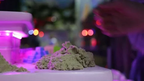 Kinetic sand flows down from the hands of women. Close-up, real-time, artificial Stock Footage 83460146
