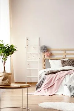 King-size bed with pink blanket and fur cushion and wooden bedhead with two p Stock Photos