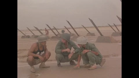 KINMEN - 1958: Men crouch among beach obstacles Stockbeeldmateriaal 342670287