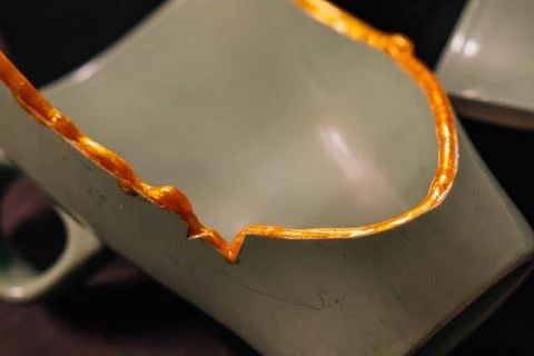 Kintsugi concept. Part of a broken pot with gold glue. Stock-Fotos
