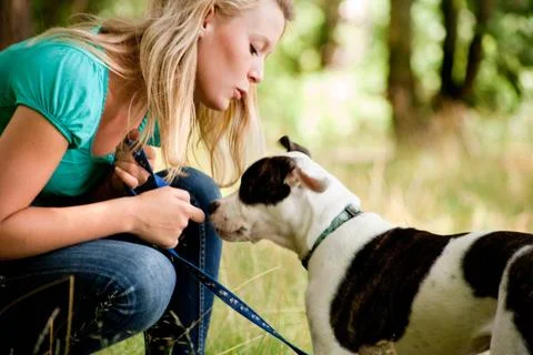 Kissing my one and only dog Blond girl and a american bulldog in the park ... Stock Photos