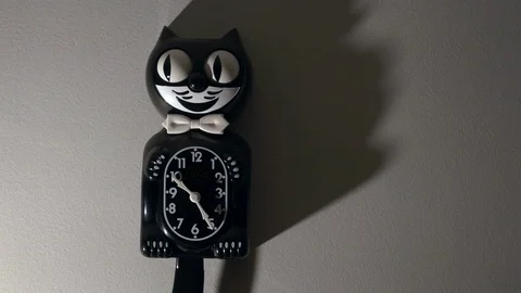 A kit cat clock in dramatic lighting hangs on a wall. Stock Footage 113632458