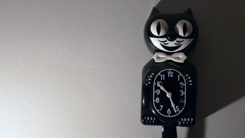 A kit cat clock in dramatic lighting hangs on a wall. Video stock 113633227