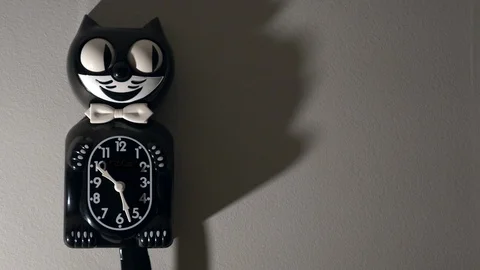 A kit cat clock in dramatic lighting hangs on a wall. Stock Footage 113633272
