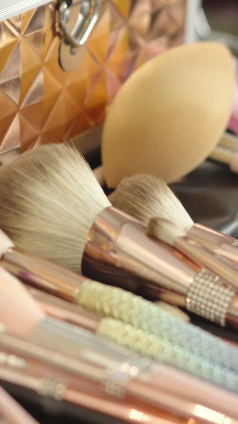Kit of makeup brushes of different sizes arranged on a table next to their case. Stock Footage 270081338