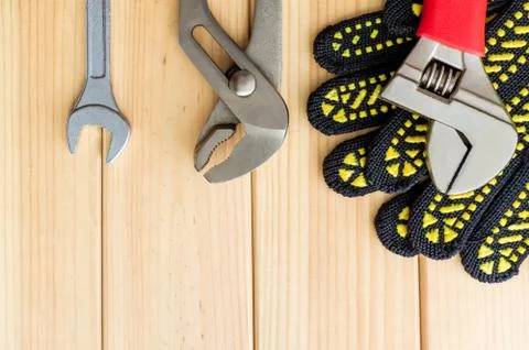 Kit of tools and work gloves for plumbers on a wooden background Stock Photos