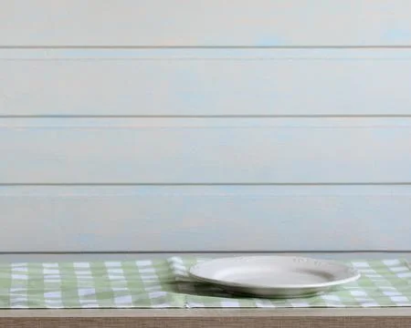 Kitchen background, an empty white plate on a green checkered towel. food mockup Stock Photos