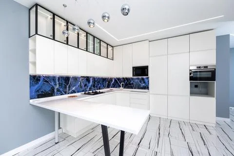A kitchen with a blue marble backsplash and white cabinets Stock Photos