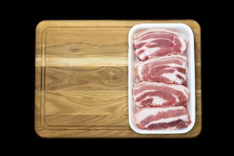 Kitchen board on a black background with a plastic container full of pork mea Stock Photos