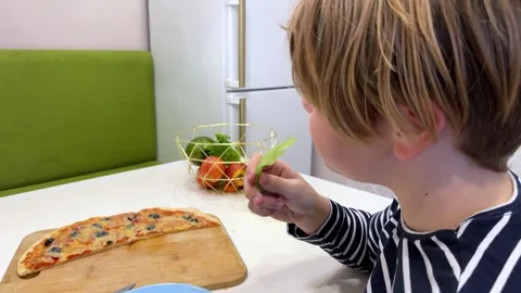 In the kitchen, the boy happily devours a slice of pizza Stock Footage 302927870