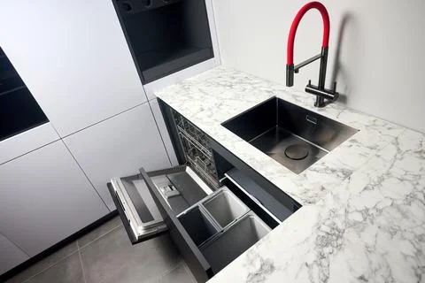 Kitchen with built-in opened dishwasher and pull out drawer for waste bin sep Stock Photos