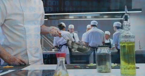 Kitchen chef flicking ingredient in pan to plate dish while team chopping under 動画素材 318012677