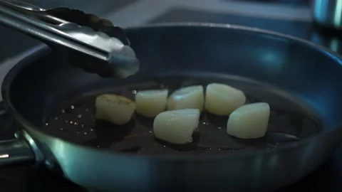 Kitchen chef flips seafood scallops on steaming skillet with metal tongs Stock Footage 141324291