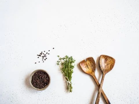 Kitchen composition with wood spoons, black pepper and fresh thyme on a light Stock Photos