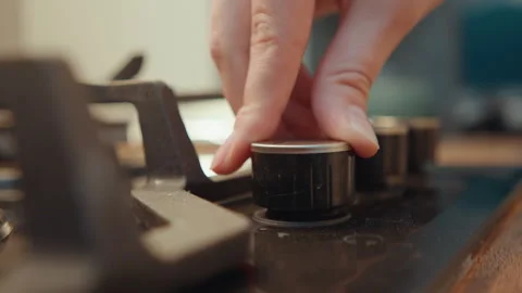 Kitchen control focus. Closeup of hand turning stove knob in cozy sunlight 库存影片 342338774
