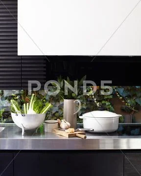 Kitchen Counter And Hob With Chopping Board And Vegetables In Colander